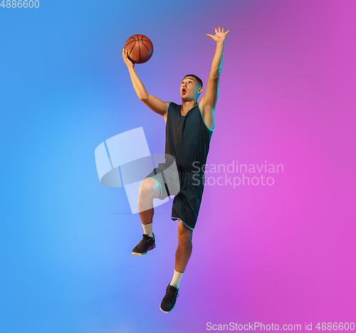 Image of Young basketball player in motion on gradient studio background in neon light