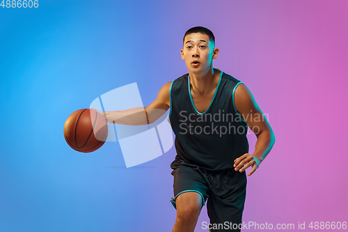 Image of Young basketball player in motion on gradient studio background in neon light