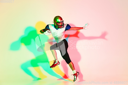 Image of American football player isolated on gradient studio background in neon light with shadows