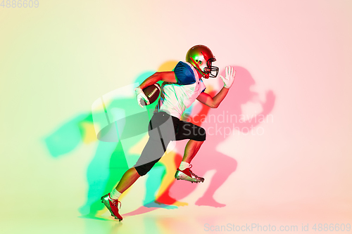Image of American football player isolated on gradient studio background in neon light with shadows