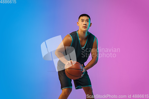 Image of Young basketball player in motion on gradient studio background in neon light