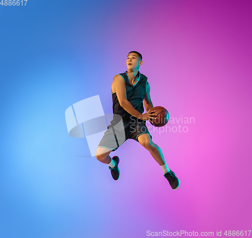 Image of Young basketball player in motion on gradient studio background in neon light