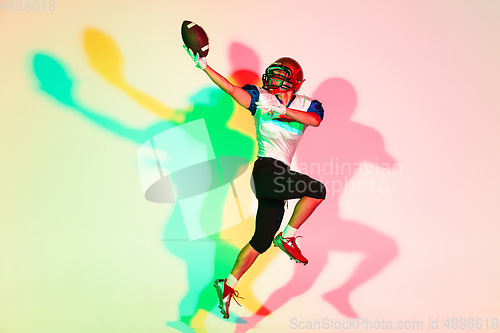 Image of American football player isolated on gradient studio background in neon light with shadows