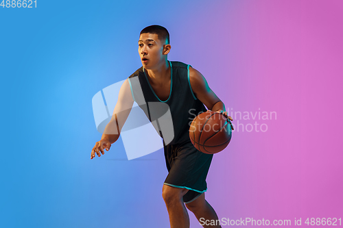Image of Young basketball player in motion on gradient studio background in neon light