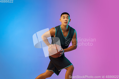 Image of Young basketball player in motion on gradient studio background in neon light