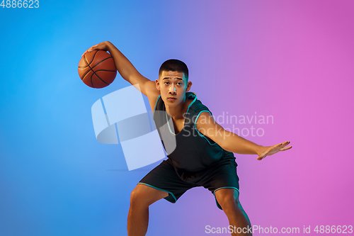 Image of Young basketball player in motion on gradient studio background in neon light