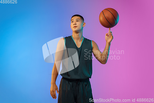 Image of Young basketball player in motion on gradient studio background in neon light