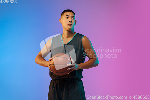 Image of Young basketball player in motion on gradient studio background in neon light
