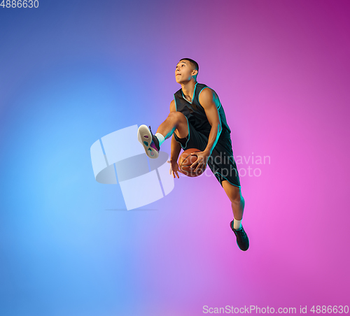 Image of Young basketball player in motion on gradient studio background in neon light