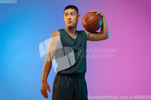 Image of Young basketball player in motion on gradient studio background in neon light