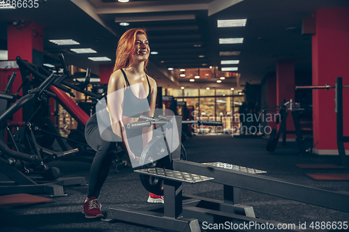 Image of Young muscular caucasian woman practicing in gym with equipment. Wellness, healthy lifestyle, bodybuilding.