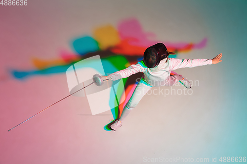 Image of Teen girl in fencing costume with sword in hand on gradient background with neon light, top view