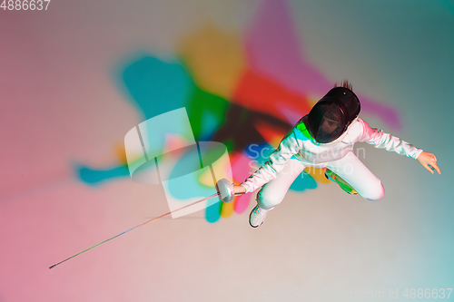 Image of Teen girl in fencing costume with sword in hand on gradient background with neon light, top view
