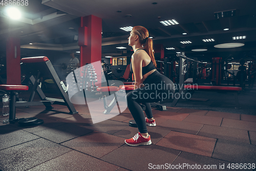 Image of Young muscular caucasian woman practicing in gym with equipment. Wellness, healthy lifestyle, bodybuilding.