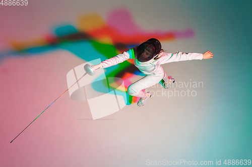 Image of Teen girl in fencing costume with sword in hand on gradient background with neon light, top view