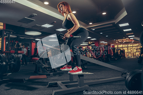 Image of Young muscular caucasian woman practicing in gym with equipment. Wellness, healthy lifestyle, bodybuilding.