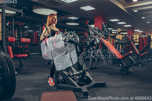 Image of Young muscular caucasian woman practicing in gym with equipment. Wellness, healthy lifestyle, bodybuilding.