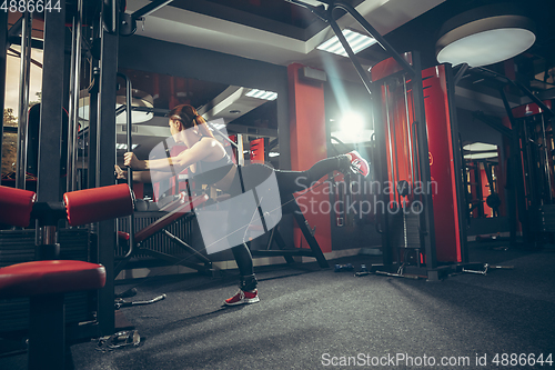 Image of Young muscular caucasian woman practicing in gym with equipment. Wellness, healthy lifestyle, bodybuilding.