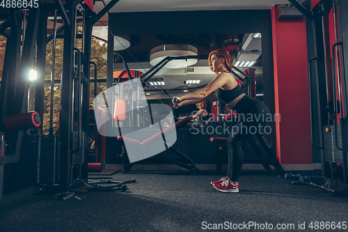 Image of Young muscular caucasian woman practicing in gym with equipment. Wellness, healthy lifestyle, bodybuilding.