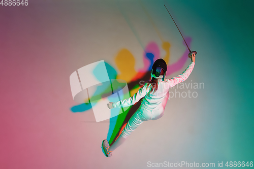 Image of Teen girl in fencing costume with sword in hand on gradient background with neon light, top view