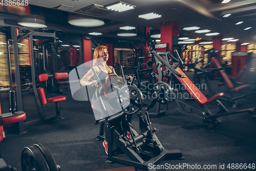 Image of Young muscular caucasian woman practicing in gym with equipment. Wellness, healthy lifestyle, bodybuilding.