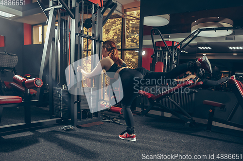 Image of Young muscular caucasian woman practicing in gym with equipment. Wellness, healthy lifestyle, bodybuilding.