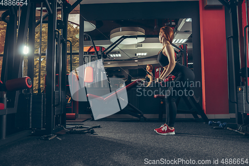 Image of Young muscular caucasian woman practicing in gym with equipment. Wellness, healthy lifestyle, bodybuilding.
