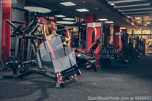 Image of Young muscular caucasian woman practicing in gym with equipment. Wellness, healthy lifestyle, bodybuilding.