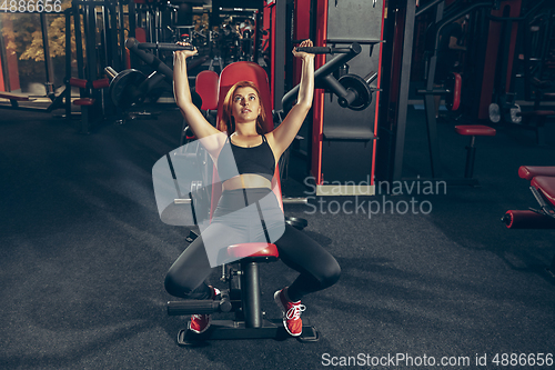 Image of Young muscular caucasian woman practicing in gym with equipment. Wellness, healthy lifestyle, bodybuilding.