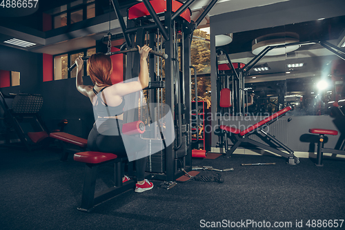 Image of Young muscular caucasian woman practicing in gym with equipment. Wellness, healthy lifestyle, bodybuilding.