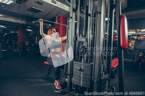 Image of Young muscular caucasian woman practicing in gym with equipment. Wellness, healthy lifestyle, bodybuilding.