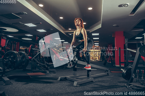 Image of Young muscular caucasian woman practicing in gym with equipment. Wellness, healthy lifestyle, bodybuilding.