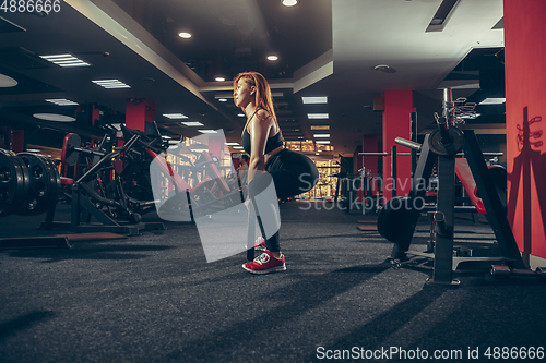 Image of Young muscular caucasian woman practicing in gym with equipment. Wellness, healthy lifestyle, bodybuilding.