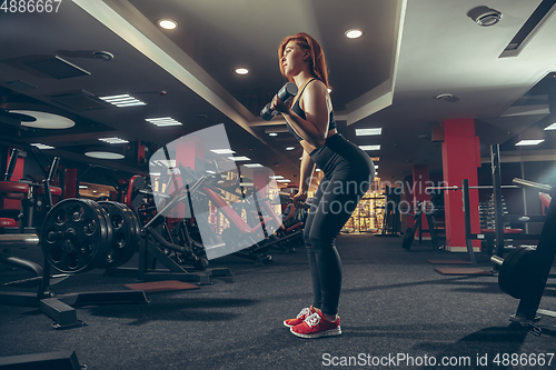 Image of Young muscular caucasian woman practicing in gym with equipment. Wellness, healthy lifestyle, bodybuilding.