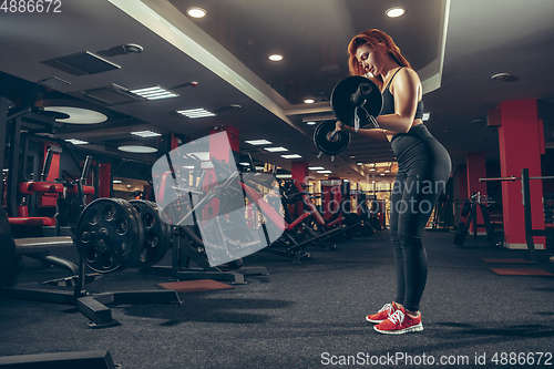 Image of Young muscular caucasian woman practicing in gym with equipment. Wellness, healthy lifestyle, bodybuilding.