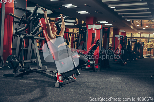 Image of Young muscular caucasian woman practicing in gym with equipment. Wellness, healthy lifestyle, bodybuilding.