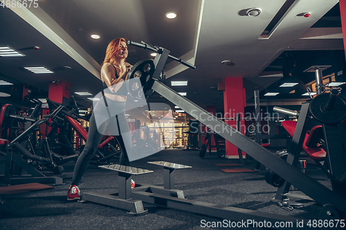 Image of Young muscular caucasian woman practicing in gym with equipment. Wellness, healthy lifestyle, bodybuilding.