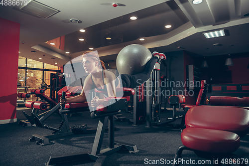 Image of Young muscular caucasian woman practicing in gym with equipment. Wellness, healthy lifestyle, bodybuilding.