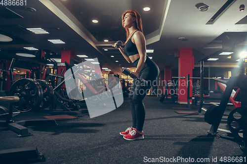 Image of Young muscular caucasian woman practicing in gym with equipment. Wellness, healthy lifestyle, bodybuilding.