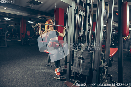 Image of Young muscular caucasian woman practicing in gym with equipment. Wellness, healthy lifestyle, bodybuilding.