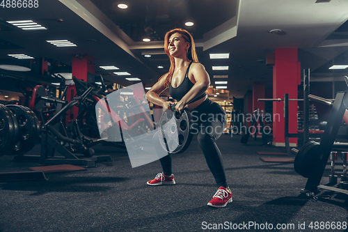 Image of Young muscular caucasian woman practicing in gym with equipment. Wellness, healthy lifestyle, bodybuilding.