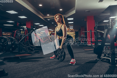 Image of Young muscular caucasian woman practicing in gym with equipment. Wellness, healthy lifestyle, bodybuilding.