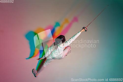 Image of Teen girl in fencing costume with sword in hand on gradient background with neon light, top view