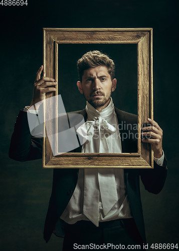 Image of Young man as Dorian Gray on dark background. Retro style, comparison of eras concept.