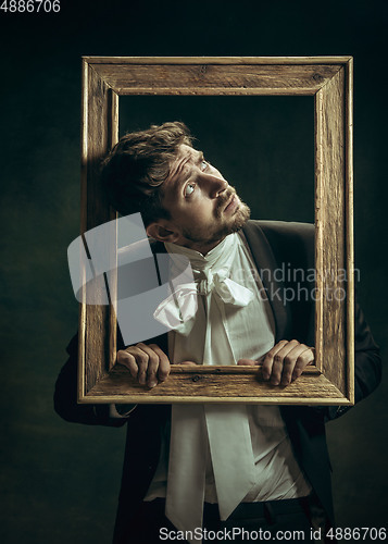 Image of Young man as Dorian Gray on dark background. Retro style, comparison of eras concept.