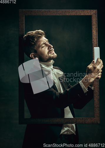 Image of Young man as Dorian Gray on dark background. Retro style, comparison of eras concept.