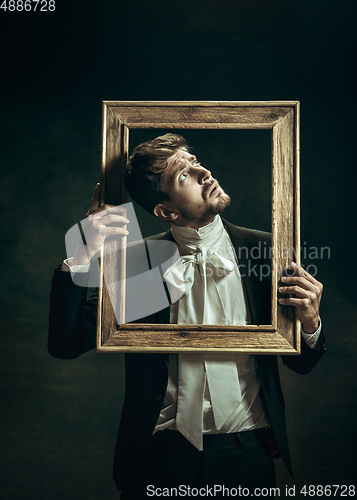 Image of Young man as Dorian Gray on dark background. Retro style, comparison of eras concept.