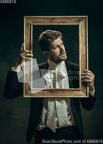 Image of Young man as Dorian Gray on dark background. Retro style, comparison of eras concept.