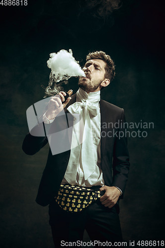 Image of Young man as Dorian Gray on dark background. Retro style, comparison of eras concept.