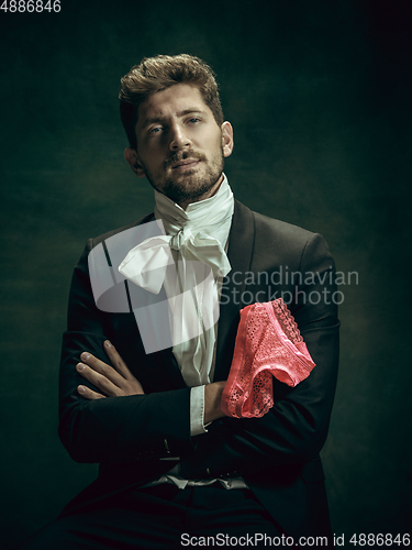 Image of Young man as Dorian Gray on dark background. Retro style, comparison of eras concept.